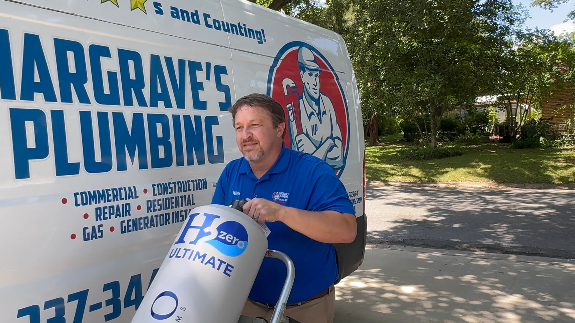 Travis Hargrave wheeling a HALO H2 Zero Ultimate water filtration system on a hand truck in front of a Hargrave’s Plumbing van